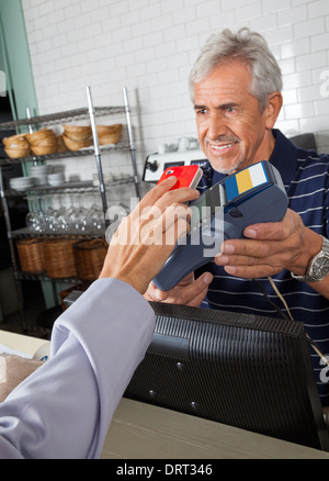 Kunden zahlen über Mobiltelefon im Store Stockfoto