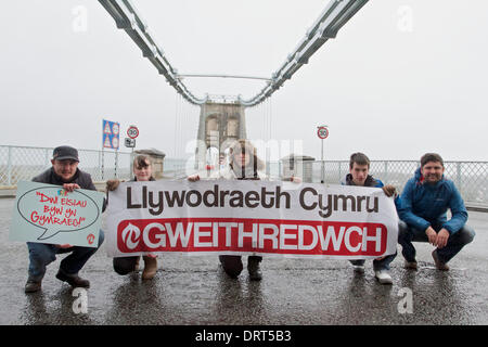 Menai Bridge, North Wales, UK. 1. Februar 2014. Mitglieder von Cymdeithas Jahr Iaith Gymraeg (Welsh Language Society) protestieren bei Brücken in ganz Wales Waliser Regierung, mehr zu tun für den Schutz der walisischen Sprache. Dieses Bild, aufgenommen am 1. Februar 2014 an der Menai Bridge, North Wales, während andere Proteste auf Brücken in ganz Wales abgehalten wurden. Weitere Presseinformationen aus der walisischen Sprache Gesellschaft Offizier Colin Nosworthy: 07971 339542 Credit: Rhys Llwyd/Alamy Live News Stockfoto