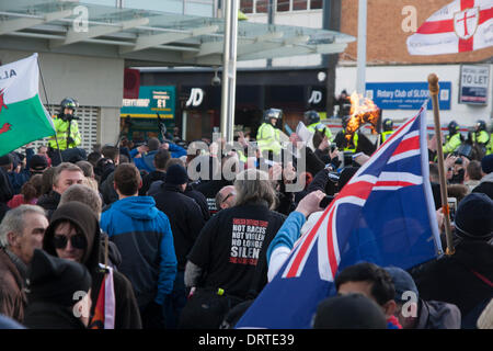 Slough, UK. 1. Februar 2014.  Eine islamische Flagge verbrennt im Hintergrund, wie mehrere hundert rechtsextreme EDL-Anhänger in Slough für eine Anti-muslimische Demonstration kommen. Bildnachweis: Paul Davey/Alamy Live-Nachrichten Stockfoto