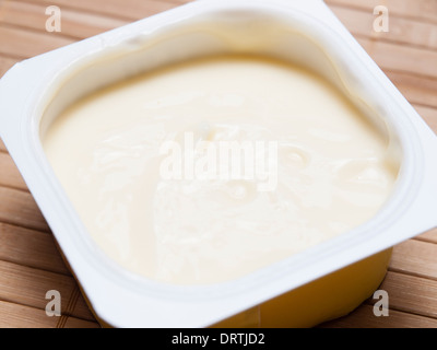 Vanille Pudding in einem Plastikbehälter auf Bambus-Hintergrund Stockfoto