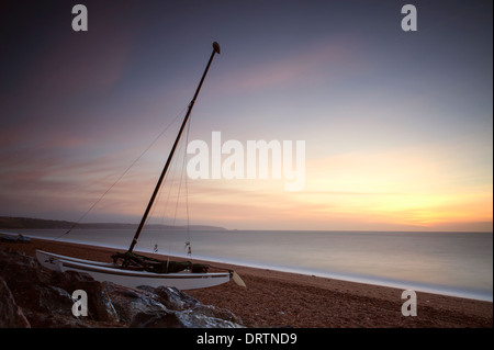 Ein kleines Segelboot am Strand von Beesands in South Devon im Sommer bei Sonnenaufgang. Stockfoto