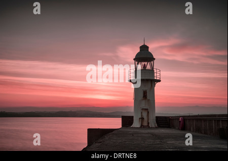 Leuchtturm und Mole in der Küstenfischerei Hafen von Brixham South Devon bei Sonnenuntergang aufgenommen. Stockfoto