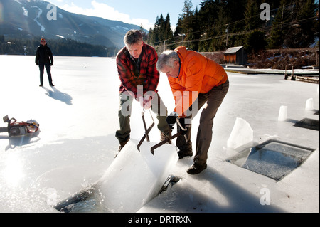 Männer ernten Eisblöcke aus einem zugefrorenen See mit einer Kettensäge, Blöcke für eine Ice carving-Wettbewerb zu ernten. Whistler, BC, Kanada Stockfoto