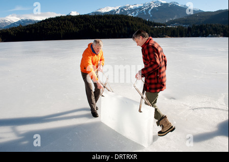 Männer ernten Eisblöcke aus einem zugefrorenen See mit einer Kettensäge, Blöcke für eine Ice carving-Wettbewerb zu ernten. Whistler, BC, Kanada Stockfoto