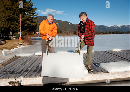 Männer ernten Eisblöcke aus einem zugefrorenen See mit einer Kettensäge, Blöcke für eine Ice carving-Wettbewerb zu ernten. Whistler, BC, Kanada Stockfoto