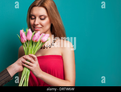 Junges schönes Mädchen gibt einen Strauß Tulpen Mann, streckte seine Hand mit einem Blumenstrauß. Valentinstag feiern Stockfoto