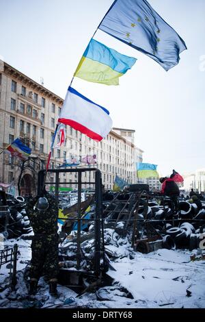 Kiew, Ukraine. 29. Januar 2014. Ein Aktivist steht in der Nähe eine Barrikade wirft eine Faust, flankiert von der Europäischen Union und der Ukraine Fahnen während einer Kundgebung der Opposition auf dem Unabhängigkeitsplatz im Zentrum von Kiew am 29. Januar 2013. Der russische Präsident Vladimir Putin vereinbart am 17. Dezember zu kaufen $ 15 Milliarden von ukrainischen Anleihen und slash seine Gasrechnung um ein Drittel zu stützen die bedrängten Regierung in Kiew, als es Massenproteste über die Ablehnung eines historischen EU-Pakts Schlachten. Zehntausende von EU-Befürworter Demonstranten strömten nach Independence Square im Herzen von Kiew nach den Gesprächen zwischen Putin und Präsident Vi Stockfoto