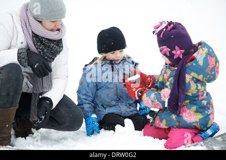 Mutter mit Töchtern spielen mit dem Schnee, winter Stockfoto