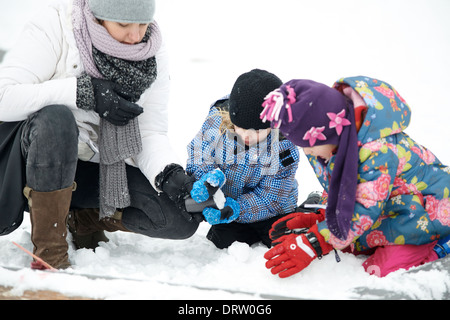 Mutter mit Töchtern spielen mit dem Schnee, winter Stockfoto