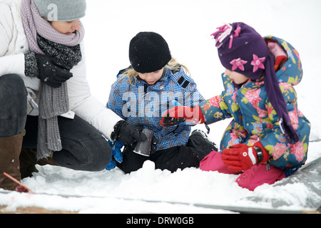 Mutter mit Töchtern spielen mit dem Schnee, winter Stockfoto