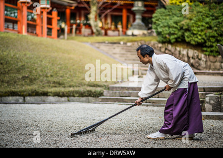 Japanischen Shinto-Priester Rechen einen Steingarten. Stockfoto