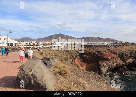 Menschen ein Spaziergang entlang der Klippen am Meer promenade in gehobenen Marina Rubicon in Playa Blanca, Lanzarote, Kanarische Inseln, Spanien Stockfoto