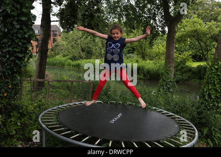 Junge Mädchen tun Star springt auf ein Trampolin im Garten durch den Fluss Gillingham Dorset-England Stockfoto