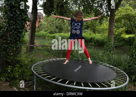 Junge Mädchen tun Star springt auf ein Trampolin im Garten durch den Fluss Stour Gillingham Dorset-England Stockfoto