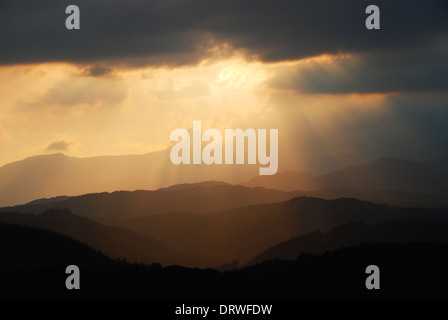 Strahlen der Sonne durch die Wolken in der Abenddämmerung über den Snowdonia Bergkette im Norden von Wales Stockfoto