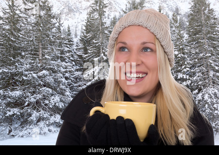 Junge, blonde Frau im Freien im Winter eine Tasse Tee trinken und nachschlagen Stockfoto