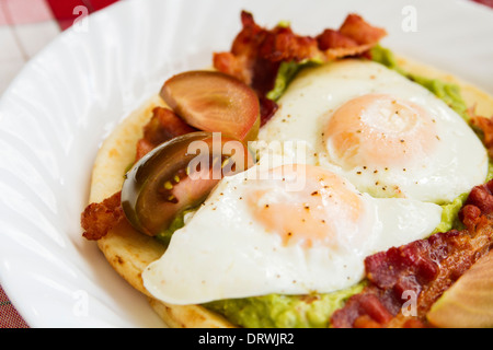 Leckeres Frühstück-Guacamole, Speck und Spiegeleier Stockfoto