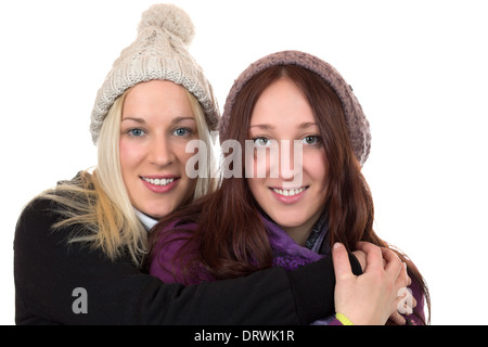 Zwei junge Frauen in Winterkleidung umarmen einander, isoliert auf weißem Hintergrund Stockfoto