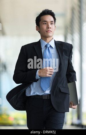 Junge chinesische Geschäftsmann laufen in einer modernen Stadt Straße Stockfoto