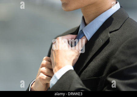 Detail eines Asiengeschäft Mann trägt einen Anzug und Anpassung seiner blaue Krawatte hautnah. Stockfoto