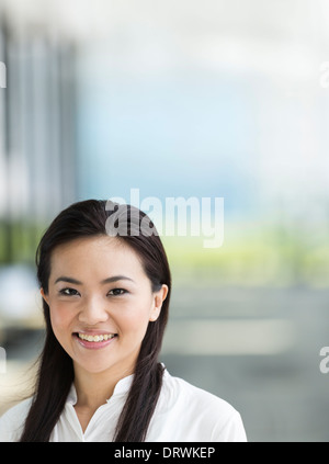 Chinesische Business-Frau in modernen asiatischen Stadt. Asiatische Geschäftsfrau lächelnd & schaut in die Kamera mit unscharf Bürogebäude ein Stockfoto