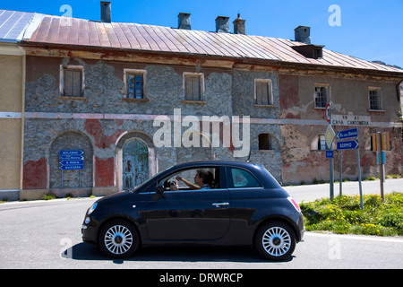 Paar in Fiat 500 passe Wegweiser auf der Stelvio Pass, Passo Dello Stelvio, Stilfser Joch, in Italien den Kopf für die Schweiz Stockfoto