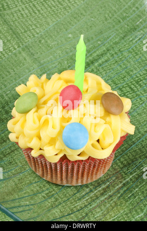 Ausgefallene Geburtstag Kuchen verziert mit kleinen bunten Zucker überzogen Schokoladenwaren und eine grüne Kerze Stockfoto