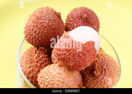 Nahaufnahme von einigen Litschis (Litschi) in einem Glas über einen hellgrünen Hintergrund. Stockfoto