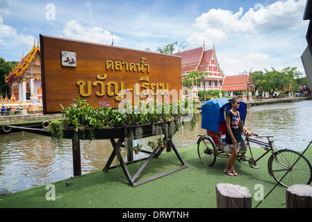 Thai schwimmenden Markt-Zeichen mit einem Touristen posieren vor es neben einem thailändischen Dreirad Stockfoto