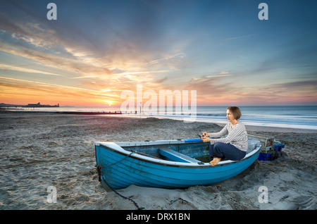 Reife Frau 50 ist bei Sonnenaufgang auf einem idyllischen Strand Tablet-Gerät verwenden. Stockfoto