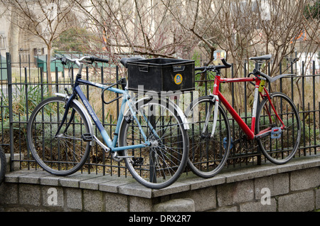 Zwei Fahrräder befestigt hoch Eisenzaun in Paris, Frankreich. Stockfoto