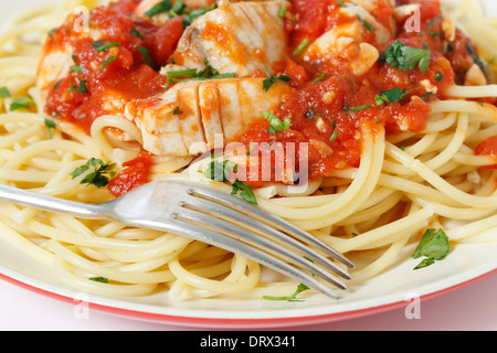 Frischer Fisch in Arrabbiata-Sauce, serviert auf Spaghetti und mit einer Gabel, Sprinked mit einer Petersilie garnieren, Nahaufnahme Stockfoto