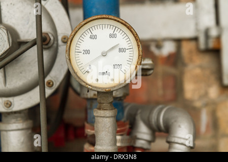 Rostige Manometer angeschlossen an Rohren mit Wand hinter Stockfoto