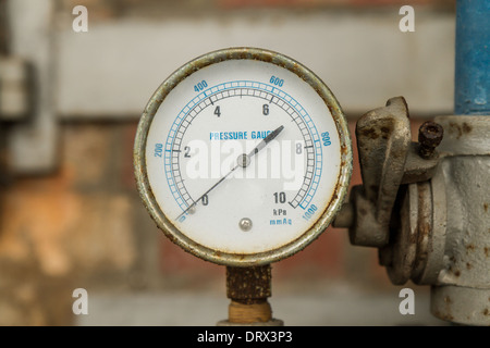 Rostige Manometer angeschlossen an Rohren mit Wand hinter Stockfoto