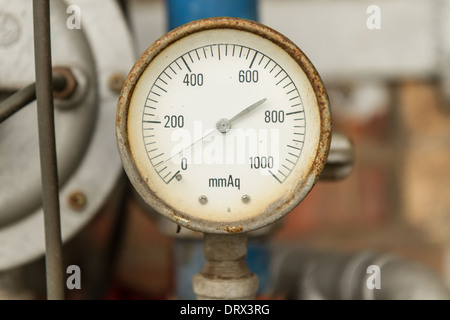 Rostige Manometer angeschlossen an Rohren mit Wand hinter Stockfoto