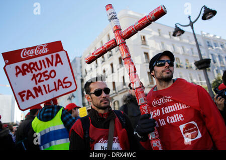 Madrid, Spanien. 2. Februar 2014. Ein Protestos hält ein Kruzifix von Coca Coladosen gemacht, während andere hält einen Banner, wo es geschrieben steht '' 1250 Familien ruinieren während einer Protestaktion in Madrid, Spanien,'' Sonntag, 2. Februar 2014. Coca-Cola-Arbeiter sind auf einen unbefristeten Streik protestieren Coca-Cola Iberian Partners Pläne schließen vier seiner 11 Anlagen und 1.253 Entlassungen. Banner auf Weste liest. Bildnachweis: Rodrigo Garcia/NurPhoto/ZUMAPRESS.com/Alamy Live-Nachrichten Stockfoto