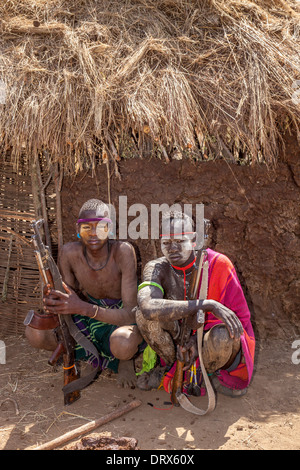 Junge Männer mit Gewehren Ouside A traditionelle Mursi Zuhause, Mursi-Dorf, das Omo-Tal, Äthiopien Stockfoto