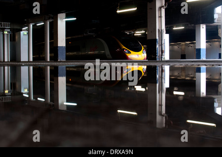 Jungfrau Pendolino-Zug am Bahnhof New Street mit Reflexion in einer Pfütze, Birmingham, UK Stockfoto