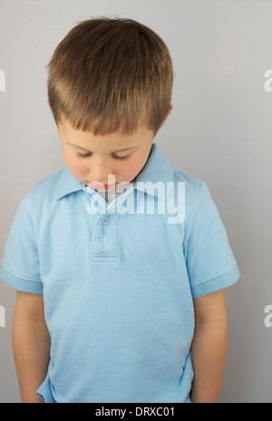 Traurige kleine Junge mit Kopf nach unten. Stockfoto