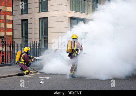 Feuerwehrleute setzen, ein Feuer auf einem Van in einer Londoner Straße Stockfoto