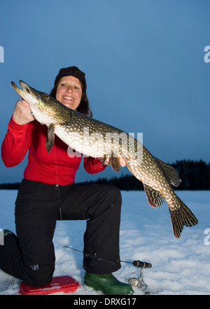 Eine Frau hält einen riesigen Hecht, dass sie Eisangeln gefangen. Stockfoto