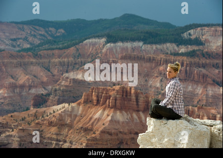 Eine junge Frau hoch oben auf einer weißen Felsformation mit Blick auf einen riesigen Wildnis. Stockfoto