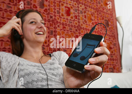 Berlin, Deutschland. 25. Januar 2014. ILLUSTRATION - hört eine junge Frau Musik mit ihrem Smartphone in Berlin, Deutschland, 25. Januar 2014. Foto: Jens Kalaene - MODEL RELEASED/Dpa/Alamy Live News Stockfoto