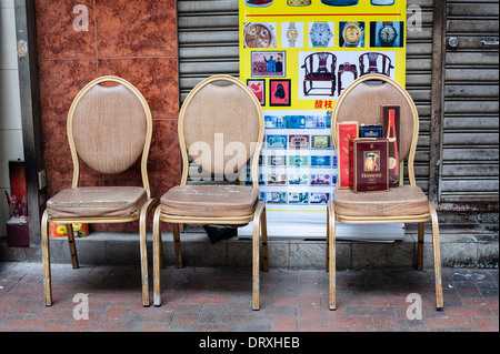 Drei Stühle mit Cognac-Flasche auf der Straße Stockfoto