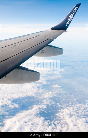 Schuss aus Flugzeugfenster, zeigt flyniki.com Logo auf Flugzeugflügel, mit blauen bewölkten Himmel über der Erde Stockfoto