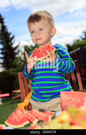 kleiner Junge eine Wassermelone essen, im Garten Stockfoto