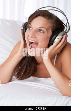 Junge Frau mit Kopfhörern singen Stockfoto