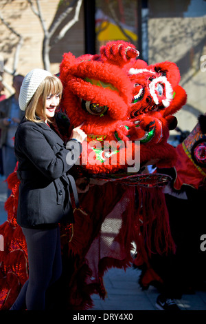 Chinesische Amerikanerin steht neben einem Drachen in Chinatown, Los Angeles früh am chinesischen Neujahrstag. Stockfoto