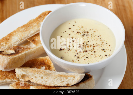 Käse-Dip mit Frischkäse, Milch, Ei und Butter in einer Bain Marie, mit Pfeffer bestreut mit Ciabata Crostini serviert gemacht. Stockfoto