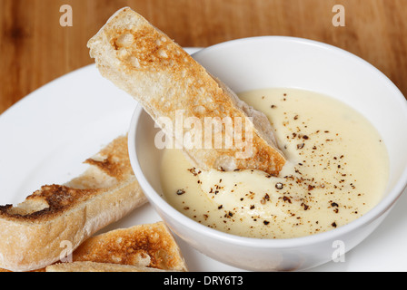 Käse-Dip mit Frischkäse, Milch, Ei und Butter in einer Bain Marie, mit Pfeffer bestreut mit Ciabata Crostini serviert gemacht. Stockfoto